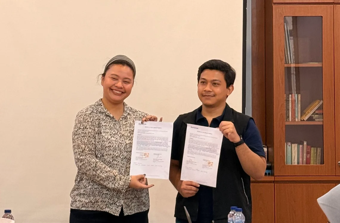 Two CaritaHub partners holding up a freshly signed partnership agreement